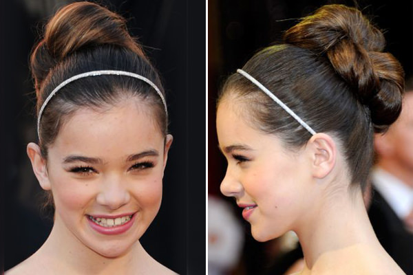 O coque alto com raiz lisa da atriz Hailee Steinfield é uma boa opção para um look mais clássico. A tiara fininha com brilho completa o visual.